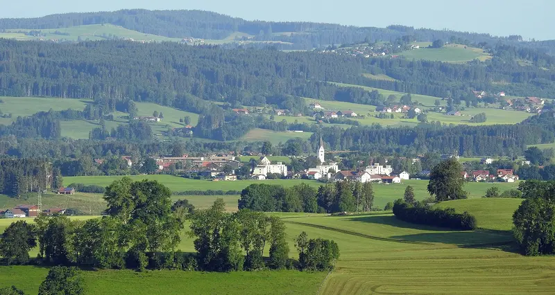 Waltenhofen von Südosten mit Kirchturm, umgeben von Wiesen, Wäldern und den Hügeln der Allgäuer Voralpen