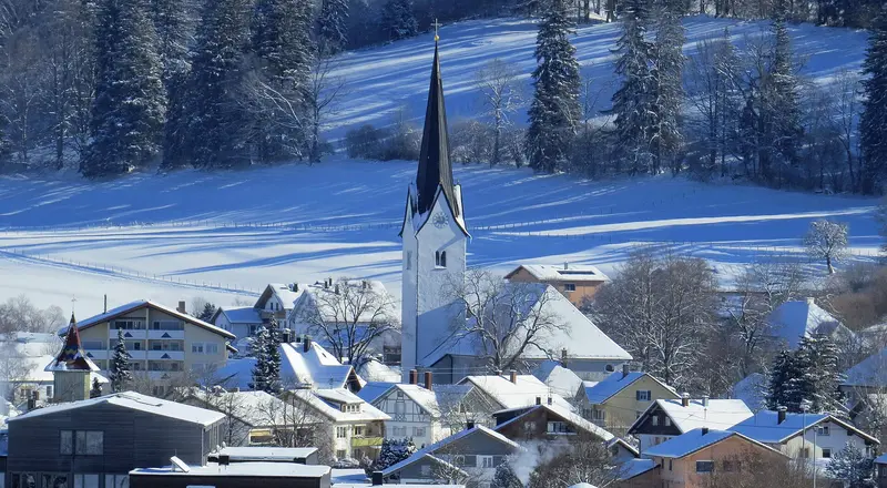 Sulzberg im Oberallgäu im Winter, Blick von Westen auf den verschneiten Ort mit dem Turm der Pfarrkirche